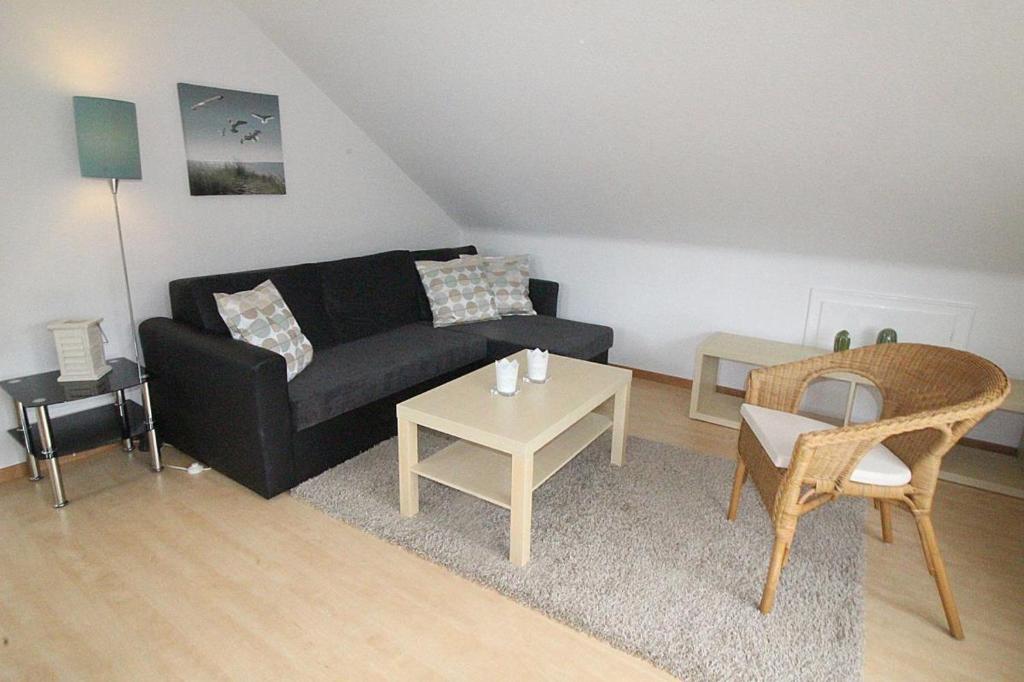 a living room with a black couch and a table at Apartmentvermittlung Mehr als Meer - Objekt 8 in Niendorf