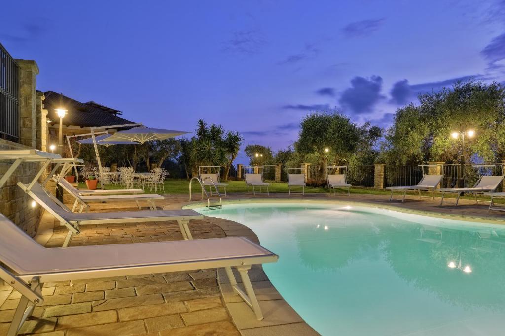 a swimming pool with tables and chairs at night at Villa Elaia in Santa Maria di Castellabate