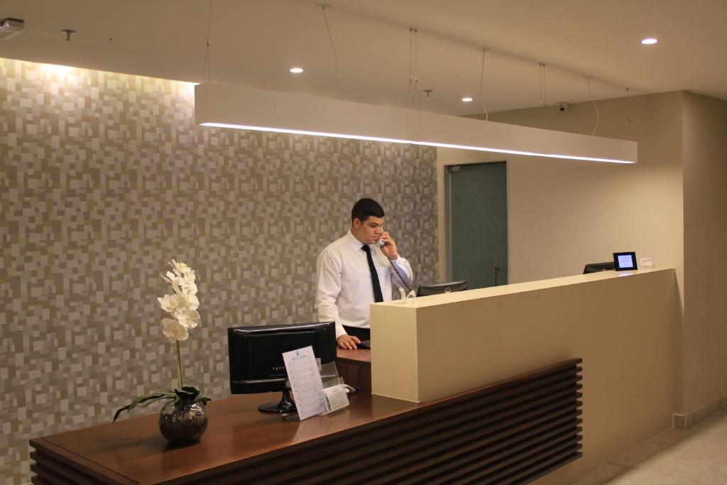 un hombre en una oficina hablando por celular en Hotel Galícia en Río de Janeiro