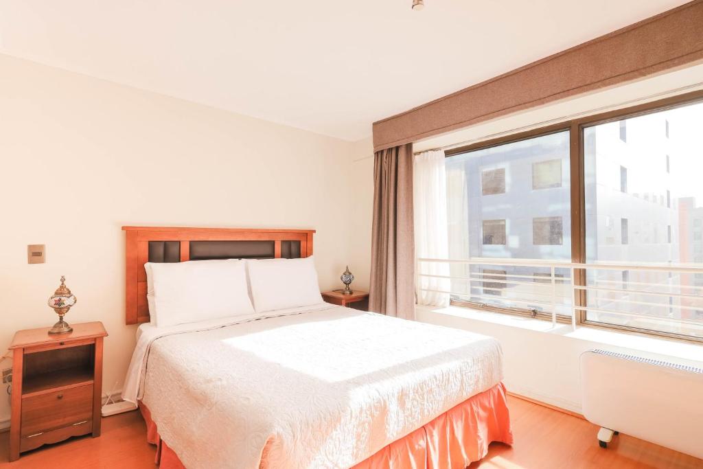 a bedroom with a bed and a large window at Mozart Studio Providencia con estacionamiento in Santiago