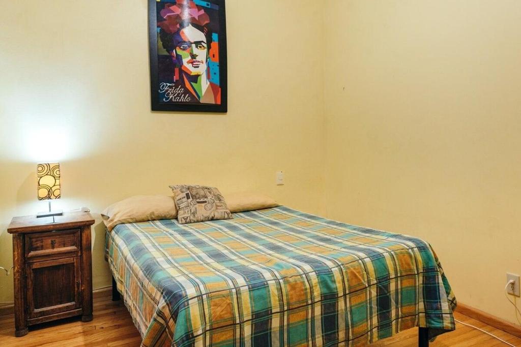 Mejor precio ubicación 2p habitación cómoda في مدينة ميكسيكو: غرفة نوم بسرير وصورة على الحائط