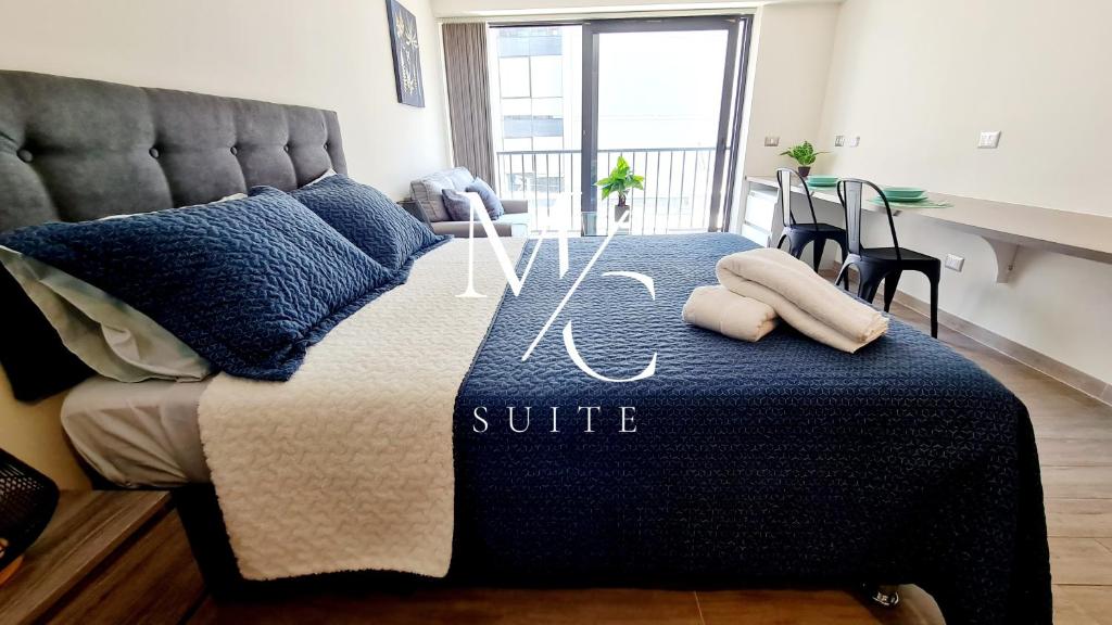 a bed with a blue comforter and pillows on it at MC SUITE Centro - Edificio Coliving in Antofagasta