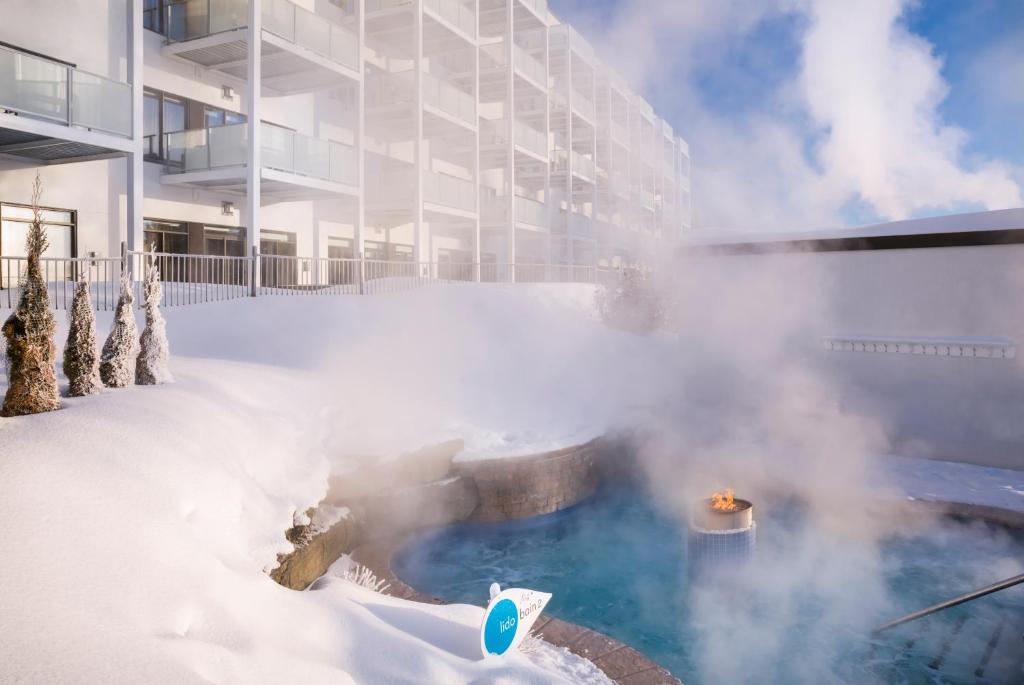un bain à remous recouvert de neige à côté d'un bâtiment dans l'établissement Estérel Resort, à Estérel