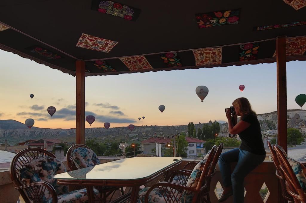 uma mulher tirando uma foto de balões de ar quente em ShoeString Stone House em Goreme