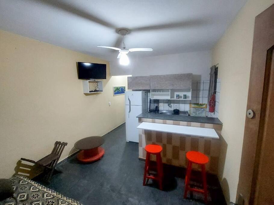cocina con encimera y taburetes rojos en una habitación en kitnet Aconchegante com simplicidade, en Ubatuba