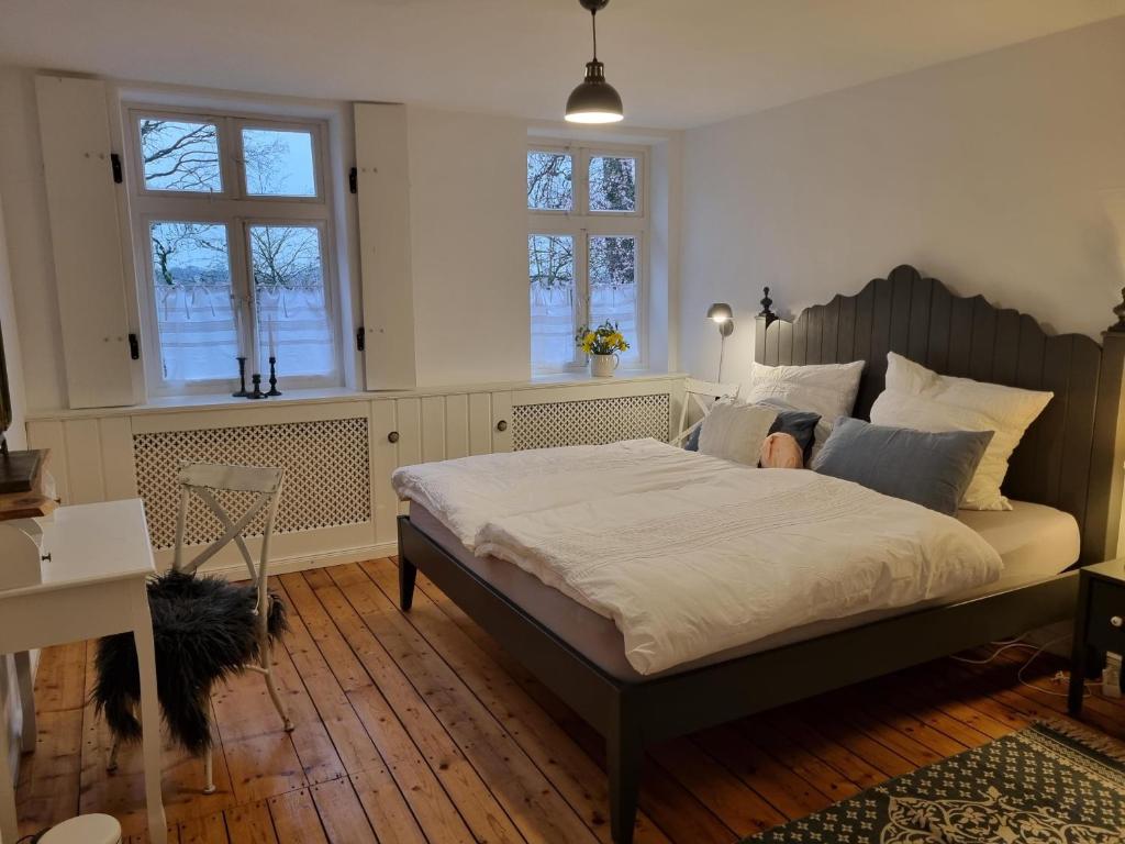 a bedroom with a large bed and two windows at NEU! Alte Schule Jarnsen Oberstübchen mit Balkon in Lachendorf