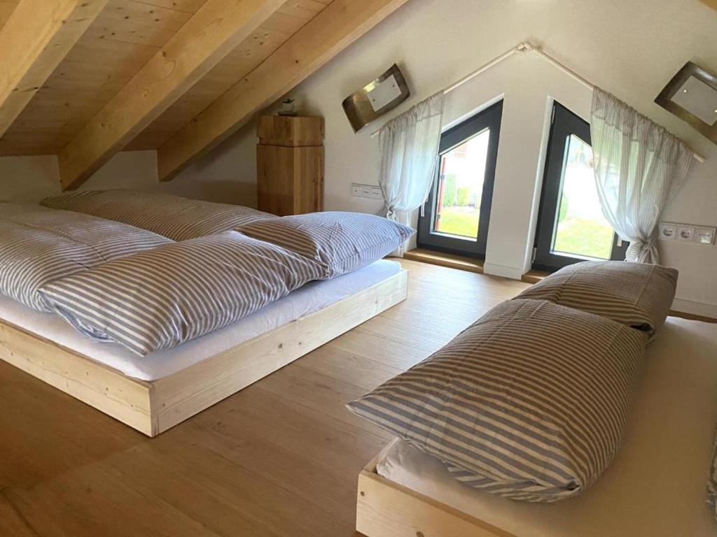 een slaapkamer met 2 bedden en 2 ramen bij Die Schorenmoos-Lodge in Dietmannsried