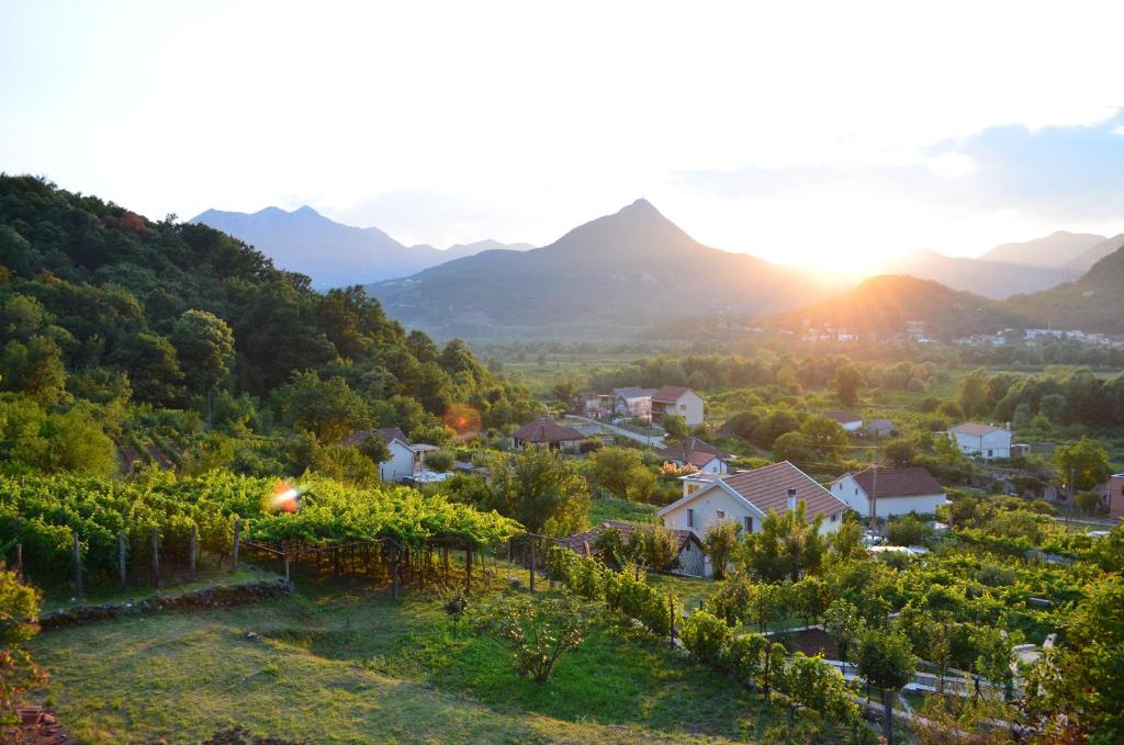 a village in a vineyard with the sun setting behind mountains at Country House Djurisic in Virpazar