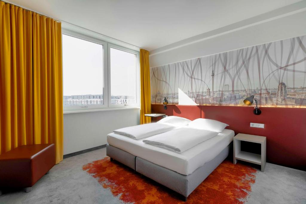 a bedroom with a bed and a large window at Campanile Berlin Brandenburg Airport in Schönefeld