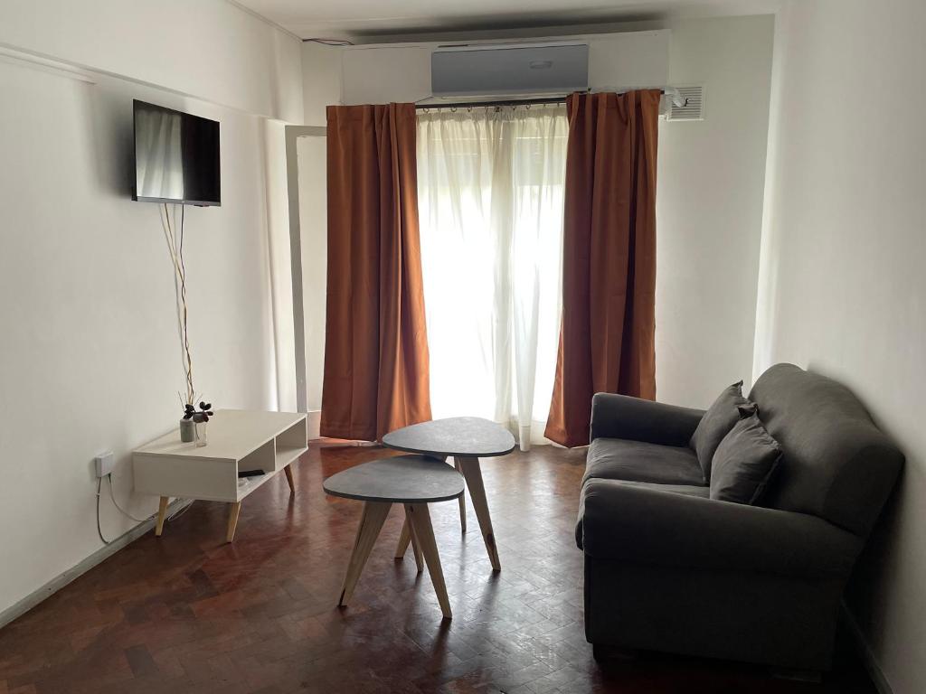 uma sala de estar com um sofá, uma mesa e uma janela em Cómodo departamento céntrico em Mendoza