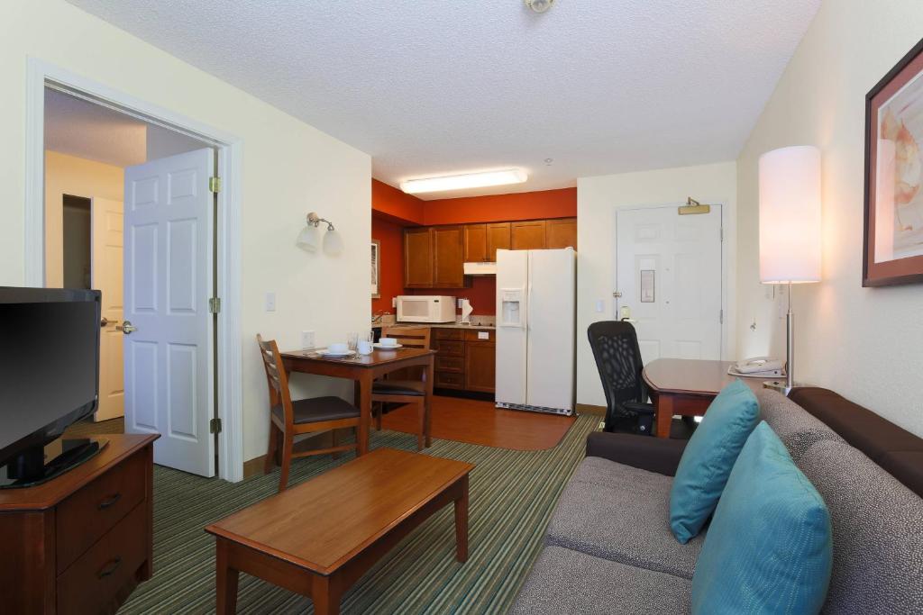 a living room with a couch and a table and a kitchen at Residence Inn by Marriott Fort Smith in Massard