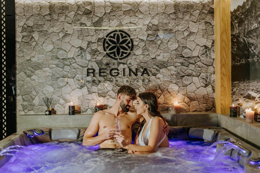 a man and a woman sitting in a hot tub at Willa Regina I Resort & SPA in Zakopane