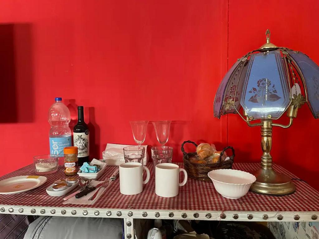 a table with plates and cups and a lamp at Habitación privada Barrio Uno in Ezeiza