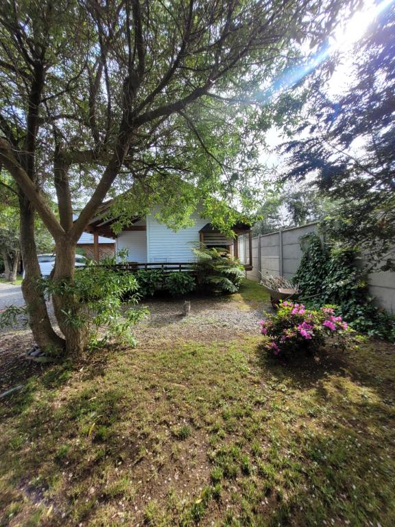 a yard with a house with a tree and flowers at Cabañas Arévalo in Futrono