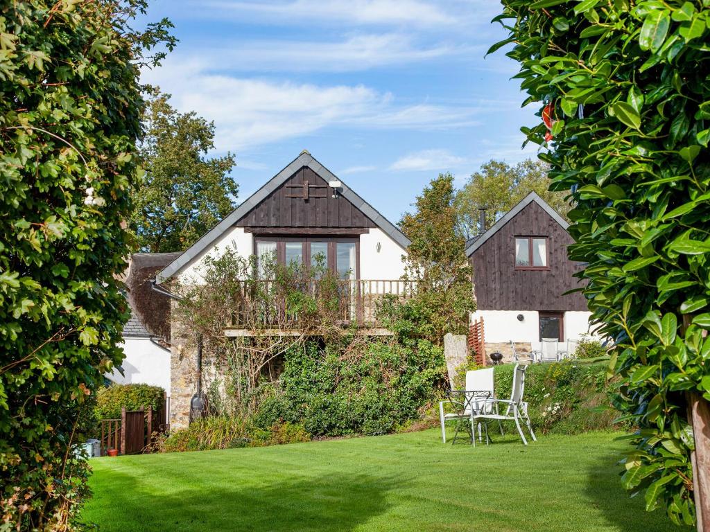 a house with a garden with two chairs in the yard at Uk45543-the Threshing Barn in Sticklepath