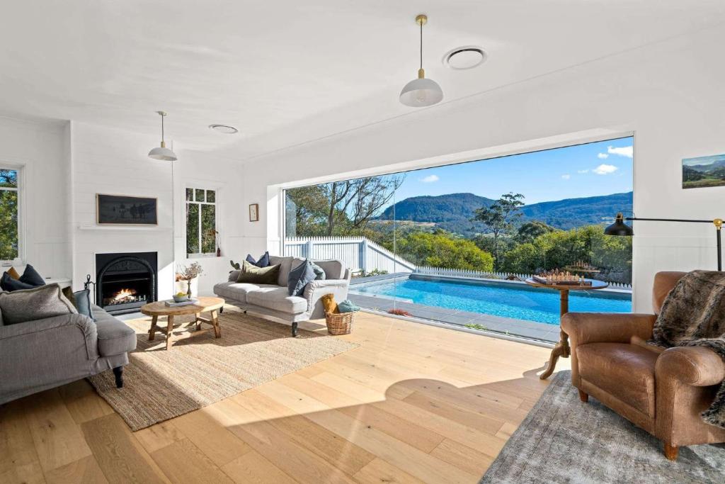 een woonkamer met een open haard en een zwembad bij Birdsong, Kangaroo Valley in Barrengarry