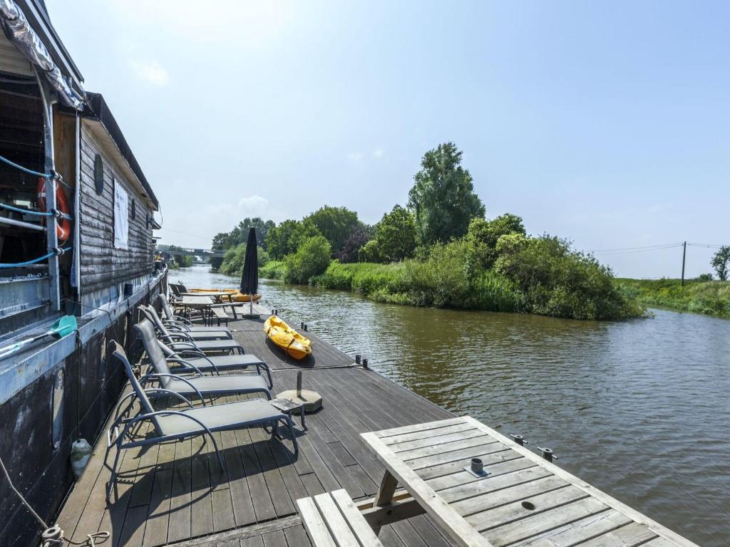 Cozy Boat in Merkem near Lake في Drie Grachten: مجموعة من الكراسي جالسين على رصيف بجوار نهر
