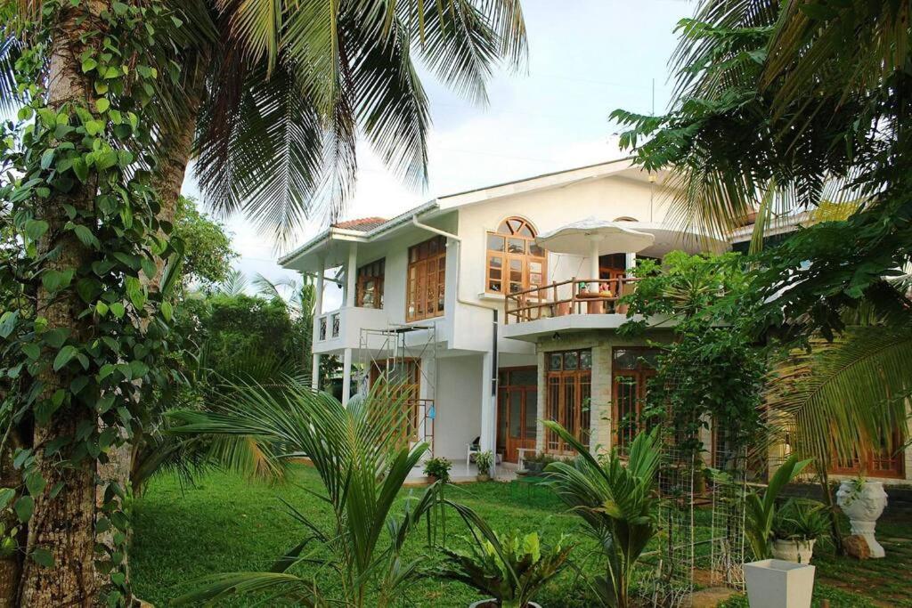 une maison avec des palmiers devant elle dans l'établissement "GreenHeart" Eco Villa - Inspire the Nature with Fresh Air- Specious Top Floor with Balcony views', à Maharagama