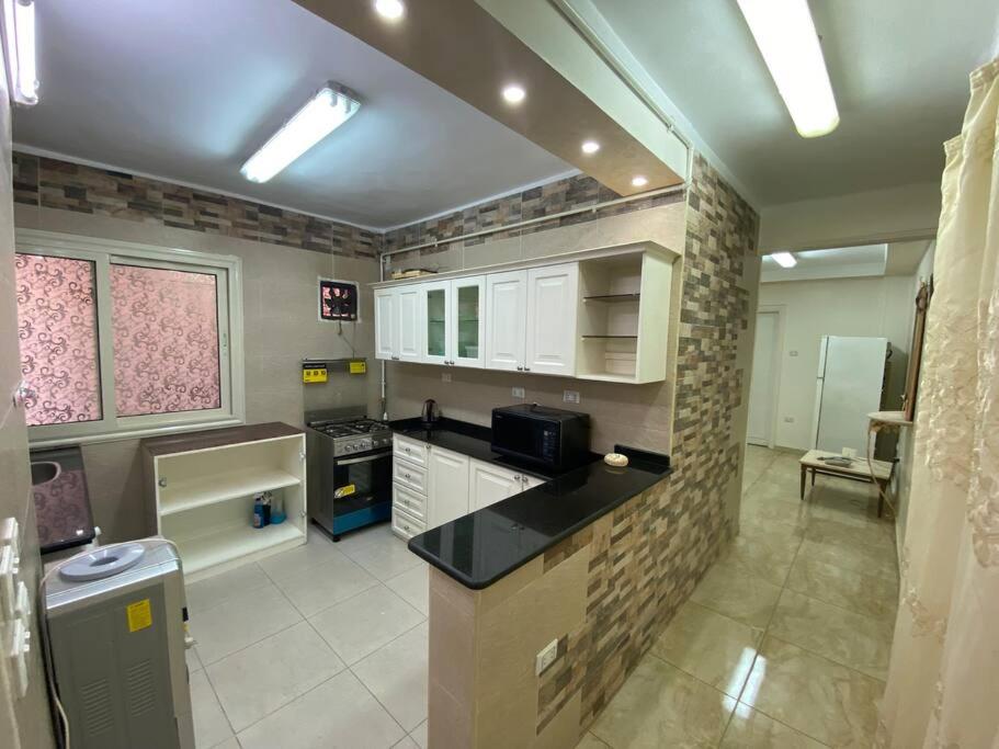 een keuken met witte kasten en een zwart aanrecht bij Apartment near airport in Caïro