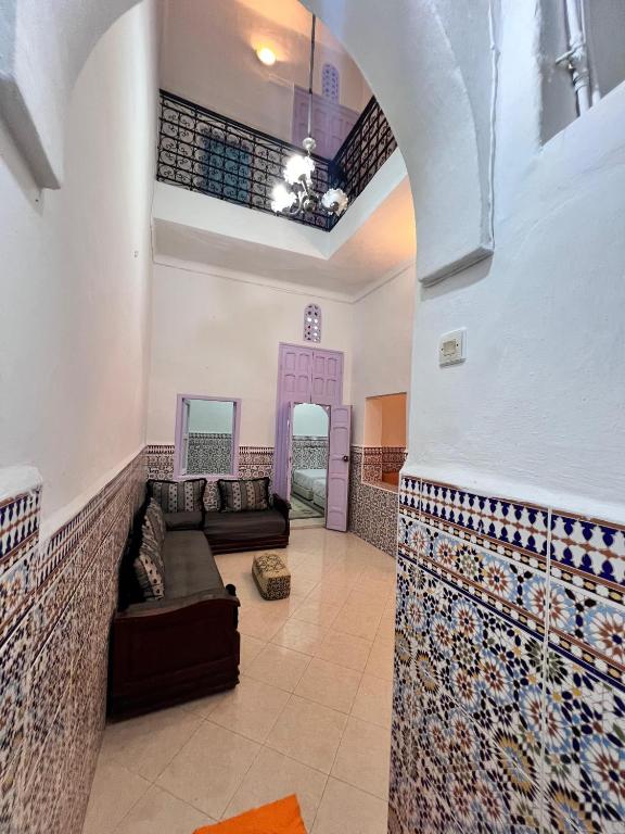 Dar mi Yamna في الرباط: غرفة معيشة مع أريكة وجدار بلاط