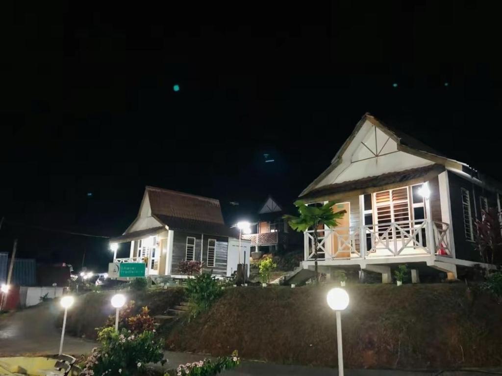 kilka domów w nocy z światłami ulicznymi w obiekcie Kurau Stone Chalet w mieście Taiping