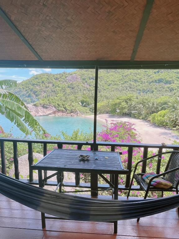 a table and a hammock on a balcony overlooking a beach at Silver cliff room 3 in Than Sadet Beach