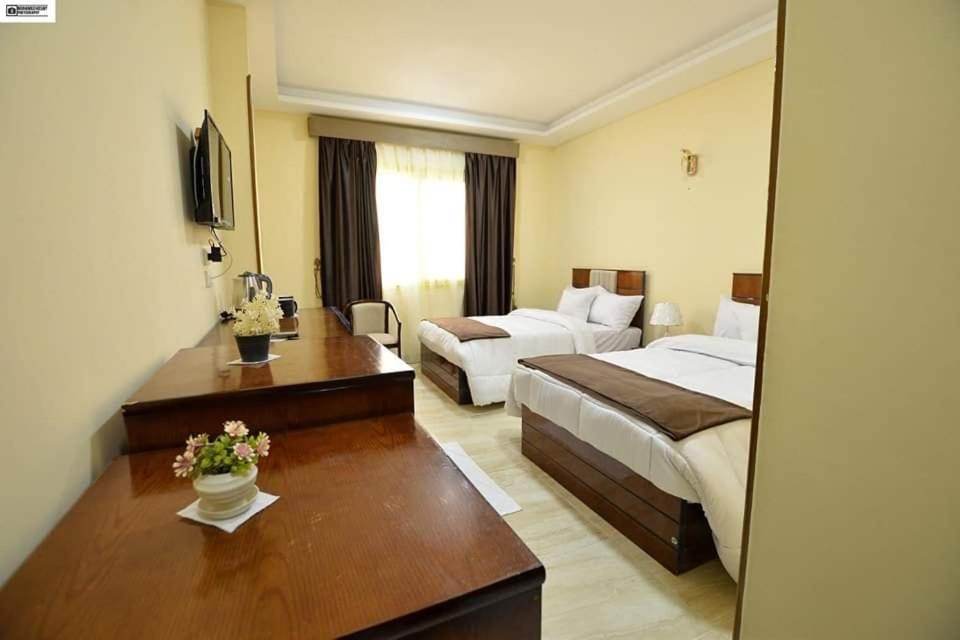 a hotel room with two beds and a desk at Nile hotel in Beni Suef