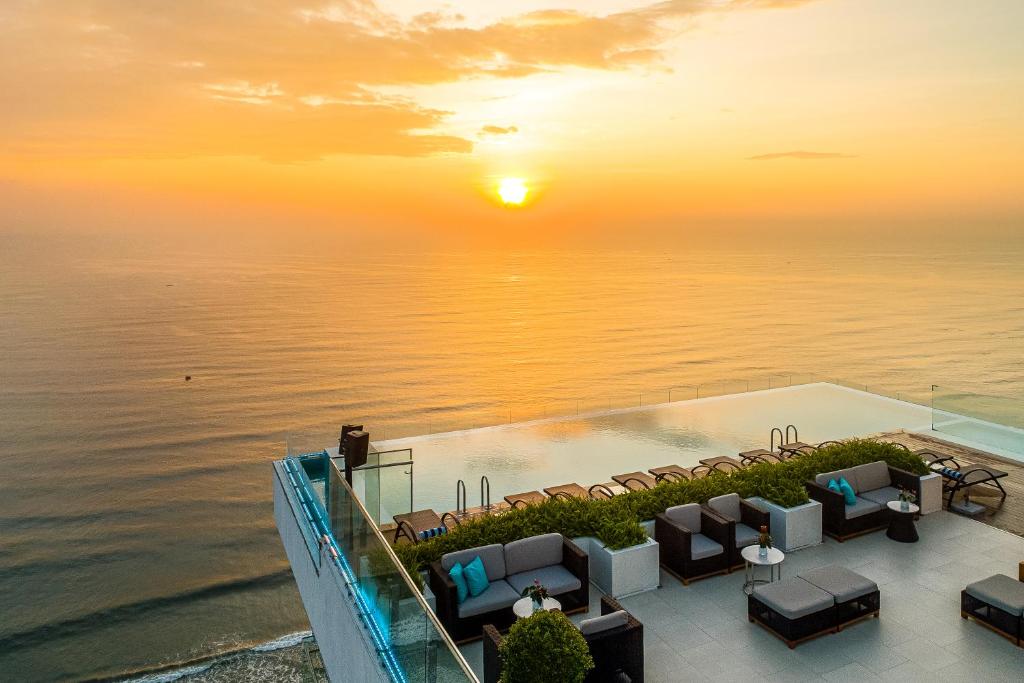 een uitzicht op de oceaan bij zonsondergang vanuit een resort bij TMS Hotel Da Nang Beach in Da Nang