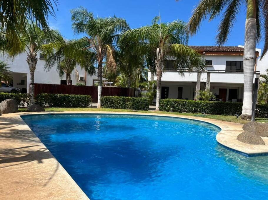 una piscina azul frente a una casa con palmeras en Full condo in Tamarindo, CR en Tamarindo