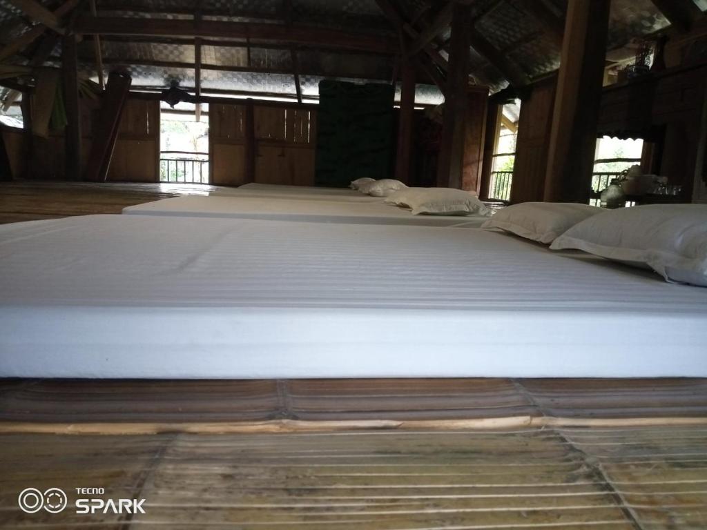 Cama grande en habitación con sábanas blancas en Puluonghomestay2, en Làng Cào