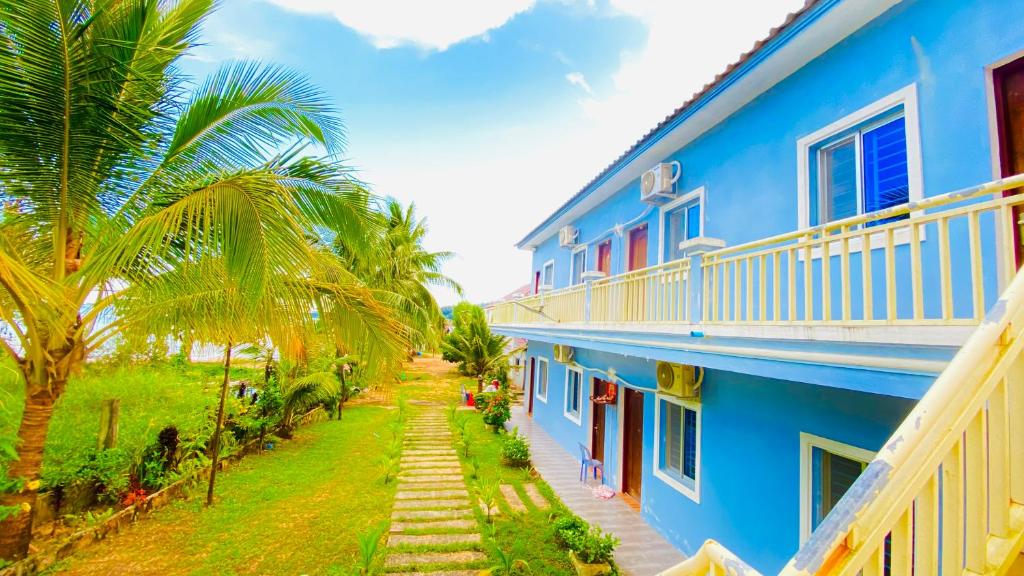瓜隆島的住宿－Koh Rong 71 Guesthouse，一座棕榈树环绕的蓝色建筑