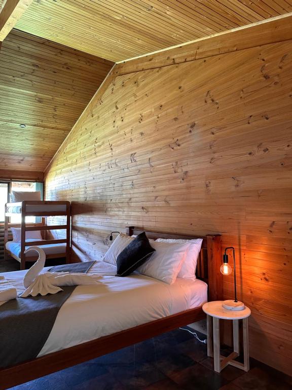 a bedroom with two beds and a wooden wall at The River Retreat Buchan in Buchan