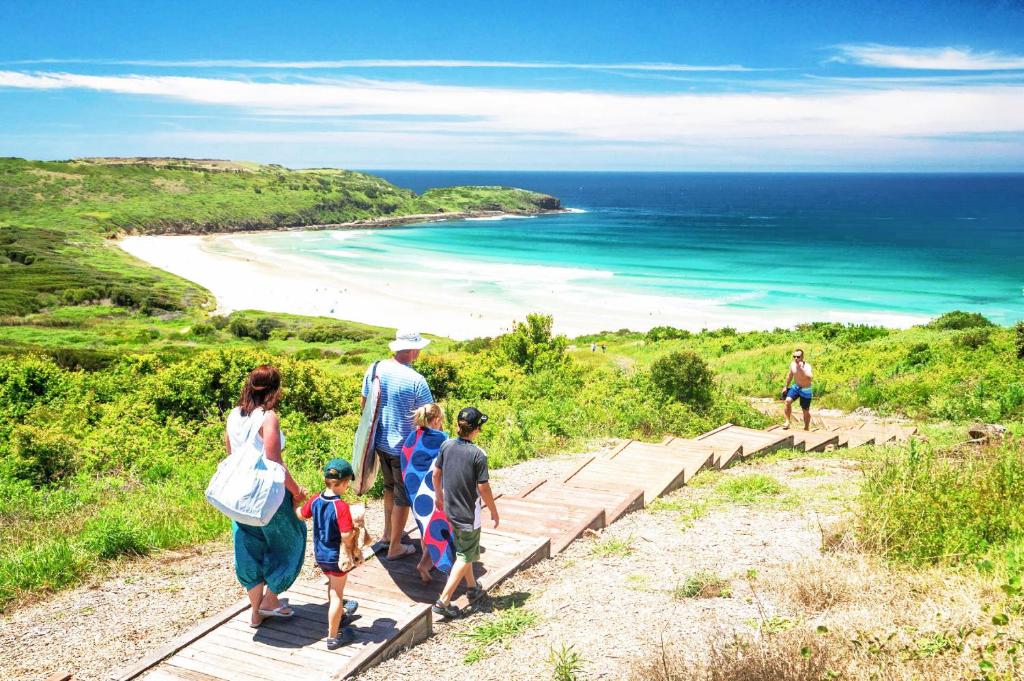 a group of people walking down the stairs to the beach at Golf Place Inn Wollongong in Primbee