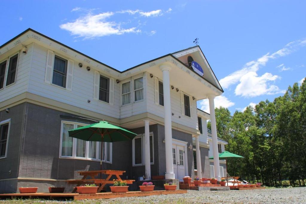 a house with an umbrella in front of it at White House ホワイト ハウス in Shimukappu