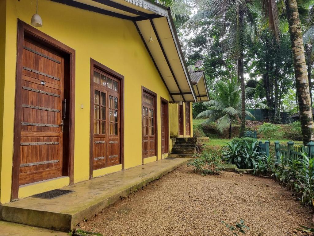 Casa amarilla con puertas de madera y patio en The Nature's Resort, Hanwella 