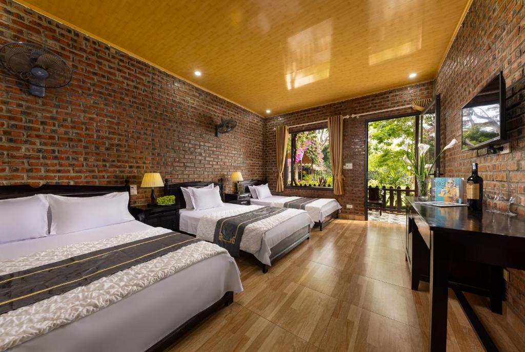 a bedroom with three beds and a brick wall at Green Homestay in Cat Ba