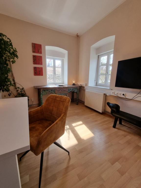 a living room with a chair and a television at Ferienwohnung am Trausdorfberg - Rosenblick in Goggitsch in Steiermark