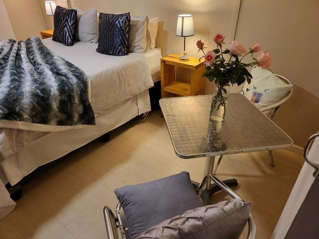um quarto com uma cama e uma mesa com um vaso de flores em Rosenhof Nut Hut - Tented Cabin under the Pecans em Clanwilliam