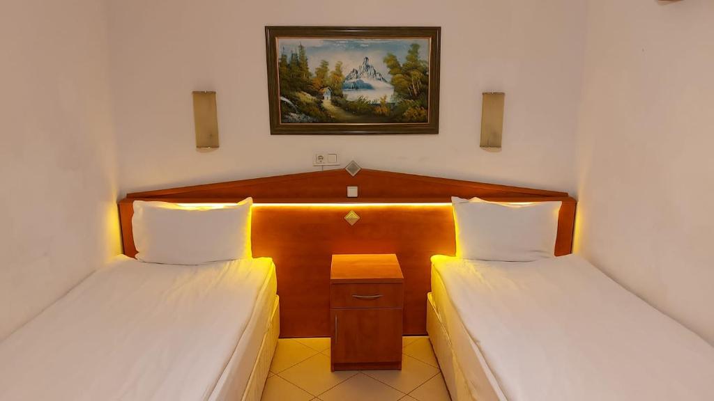 two beds in a hotel room with a picture on the wall at Beyaz Melek Hotel in Antalya
