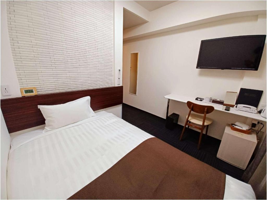 um quarto com uma cama e uma secretária com um computador em Akasaka Urban Hotel em Tóquio