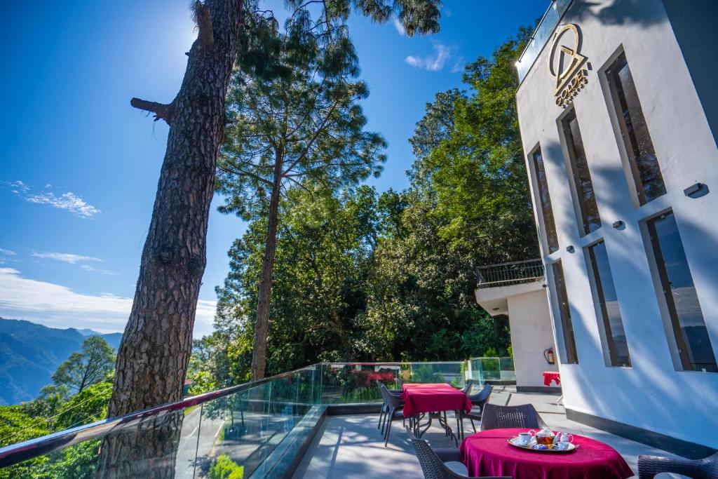 a balcony with red tables and chairs and a tree at The Golden Sunrise Hotel in Nainital