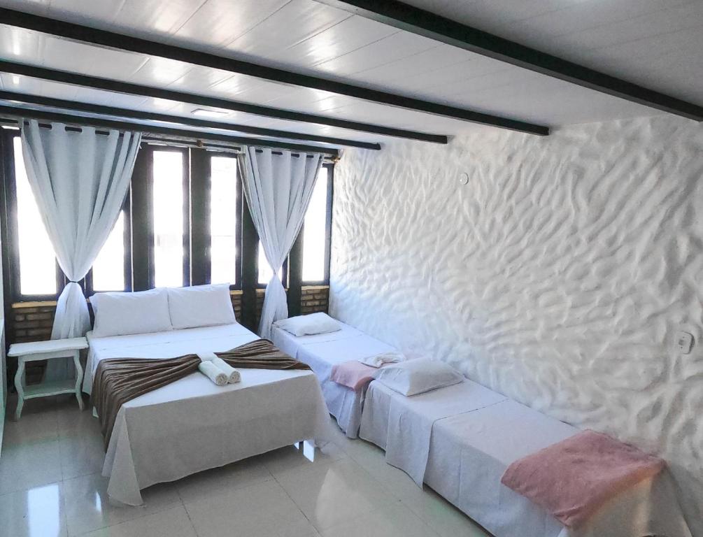 Duas camas num quarto com janelas em Nautillus Pousada em Arraial do Cabo