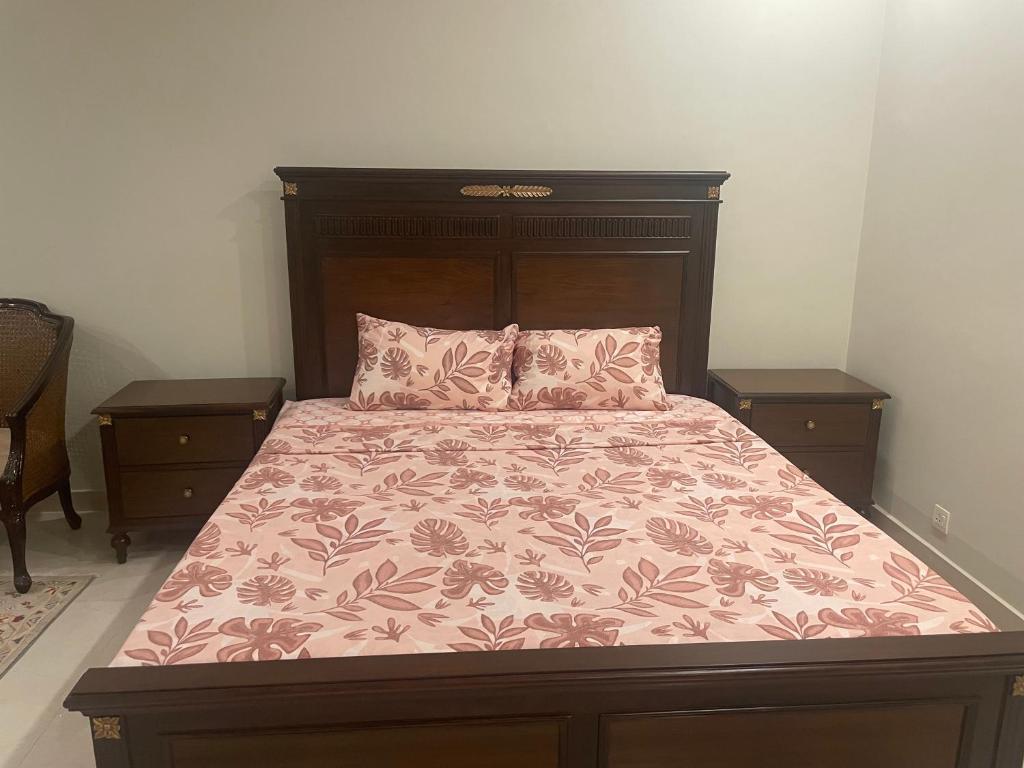 a bed with a wooden headboard and two pillows at Cozy Corner Homestay in Lahore