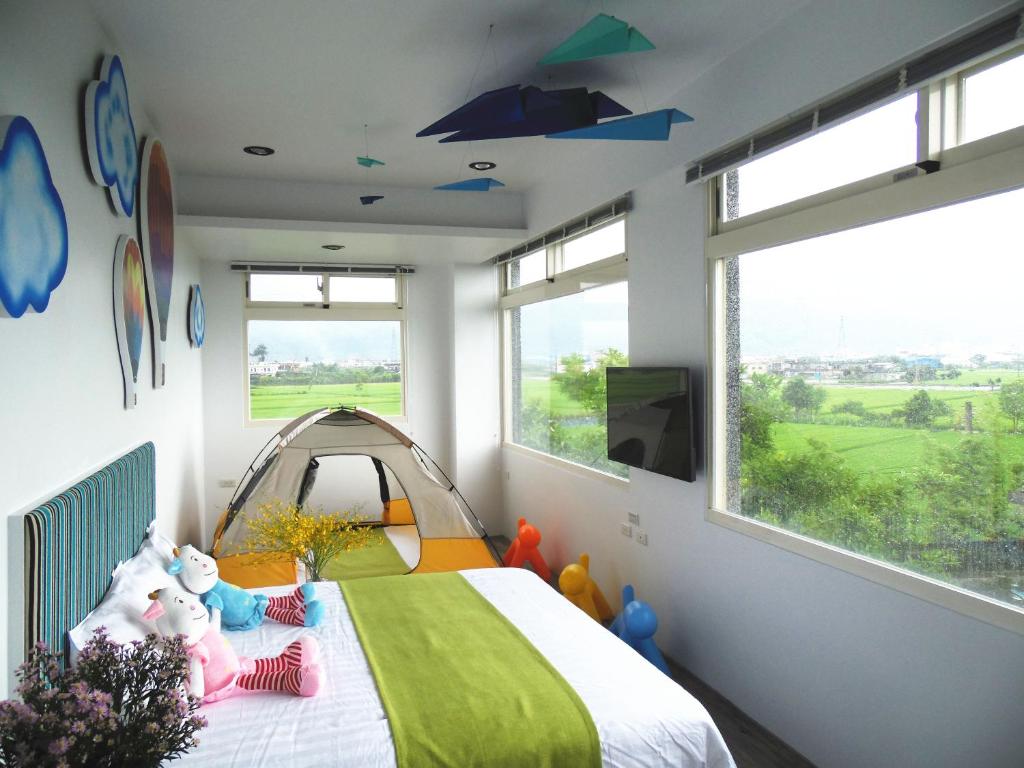 a bedroom with a bed with a tent and windows at Footprint Garden B&B in Dongshan