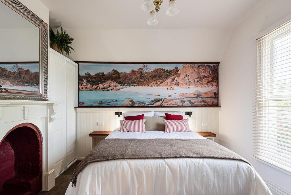 a bedroom with a bed with a painting on the wall at Mersey River Cottage ( cir 1888) Central location with Amazing Ocean and Habour Views. in Devonport