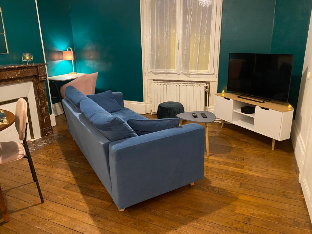 a living room with a blue couch and a television at Appartement 3 pièces avec garage in Moulins