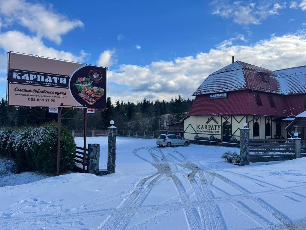 ein Schild im Schnee vor einem Gebäude in der Unterkunft Motel Karpaty in Mohnate