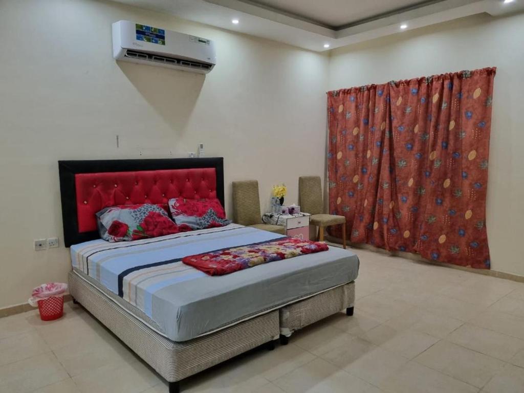 1 dormitorio con 1 cama grande y cortina roja en Budget Hostel Rooms, en Al Ain