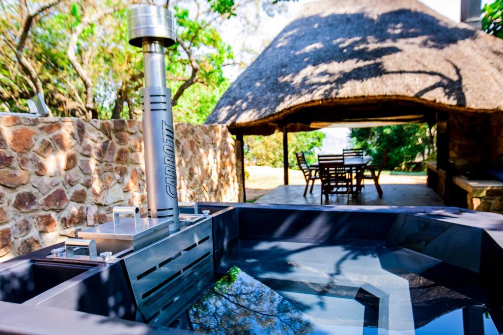 an outdoor swimming pool with a thatch roof at Wildevy at Benlize in Hartbeespoort
