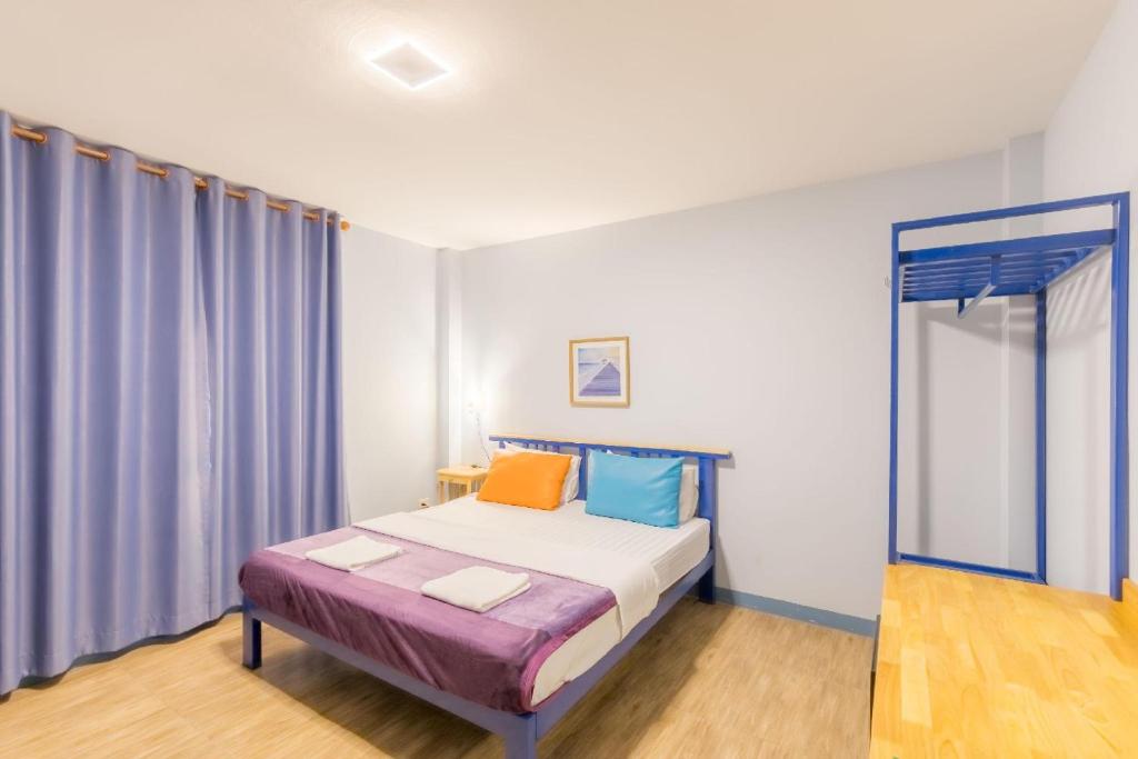 um pequeno quarto com uma cama com cortinas azuis em Blueplace บลูเพลส em Ban Talat Rangsit